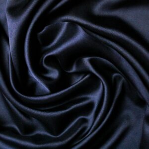 Close-up of smooth black satin fabric with elegant folds creating a luxurious texture.